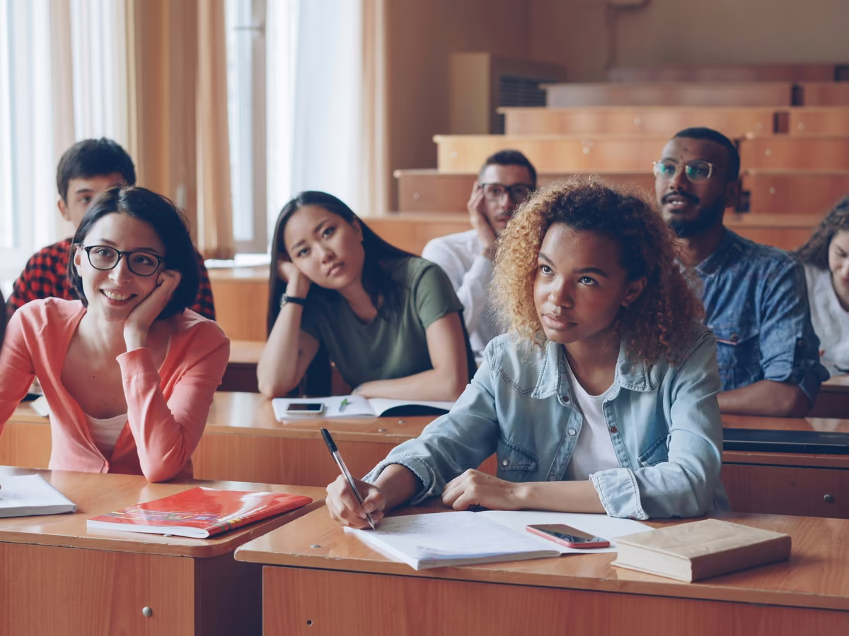 Students in a lecture hall, one turning to smile