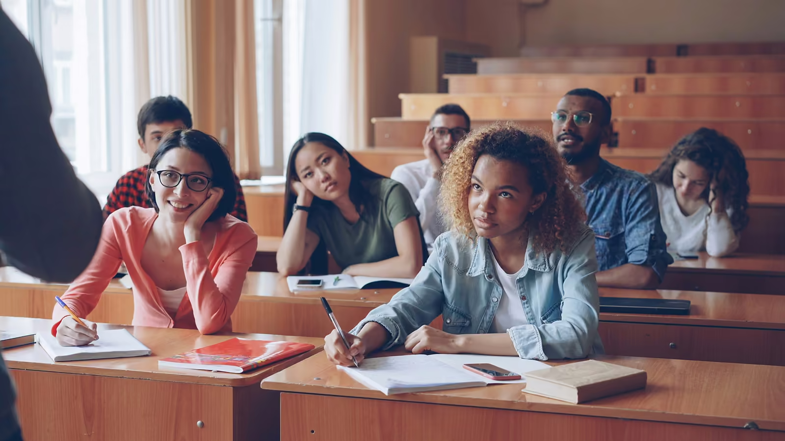 Students in a lecture hall, one turning to smile