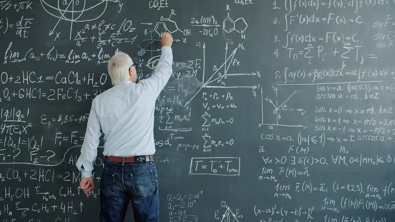 A teacher writing formulas across a blackboard