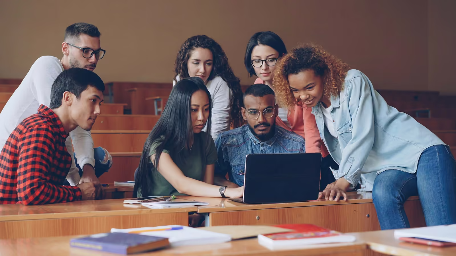 A group of students gathered around one laptop