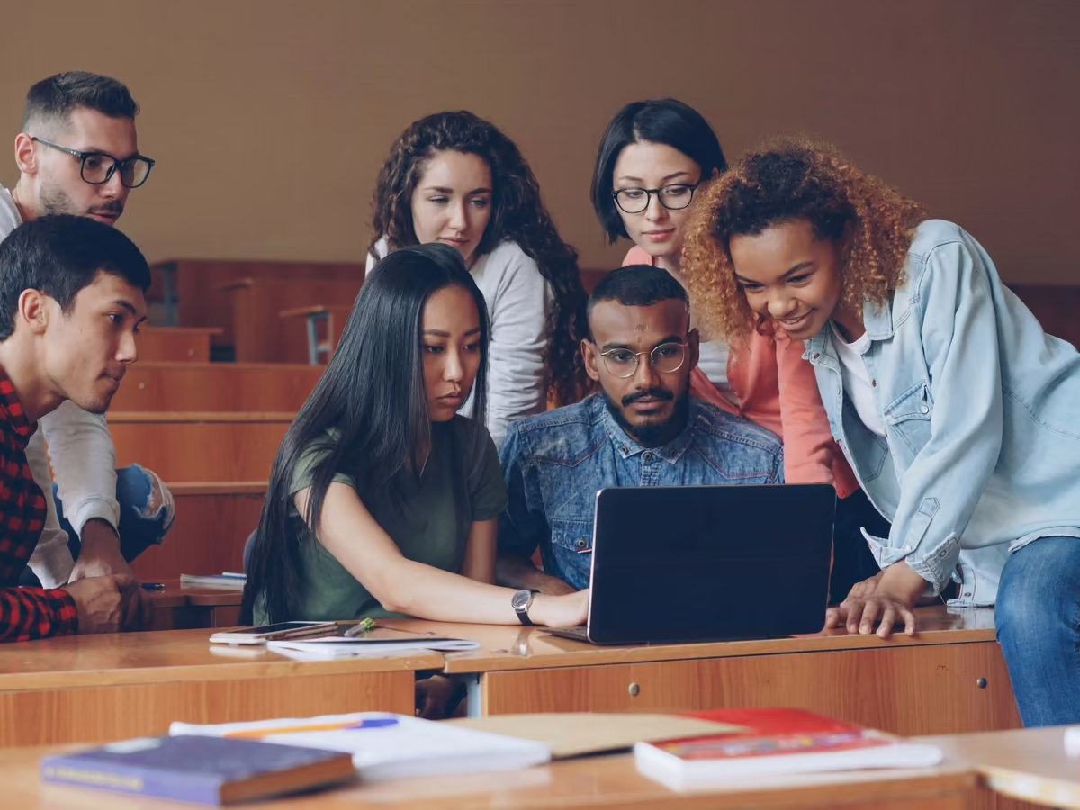 A group of students gathered around one laptop