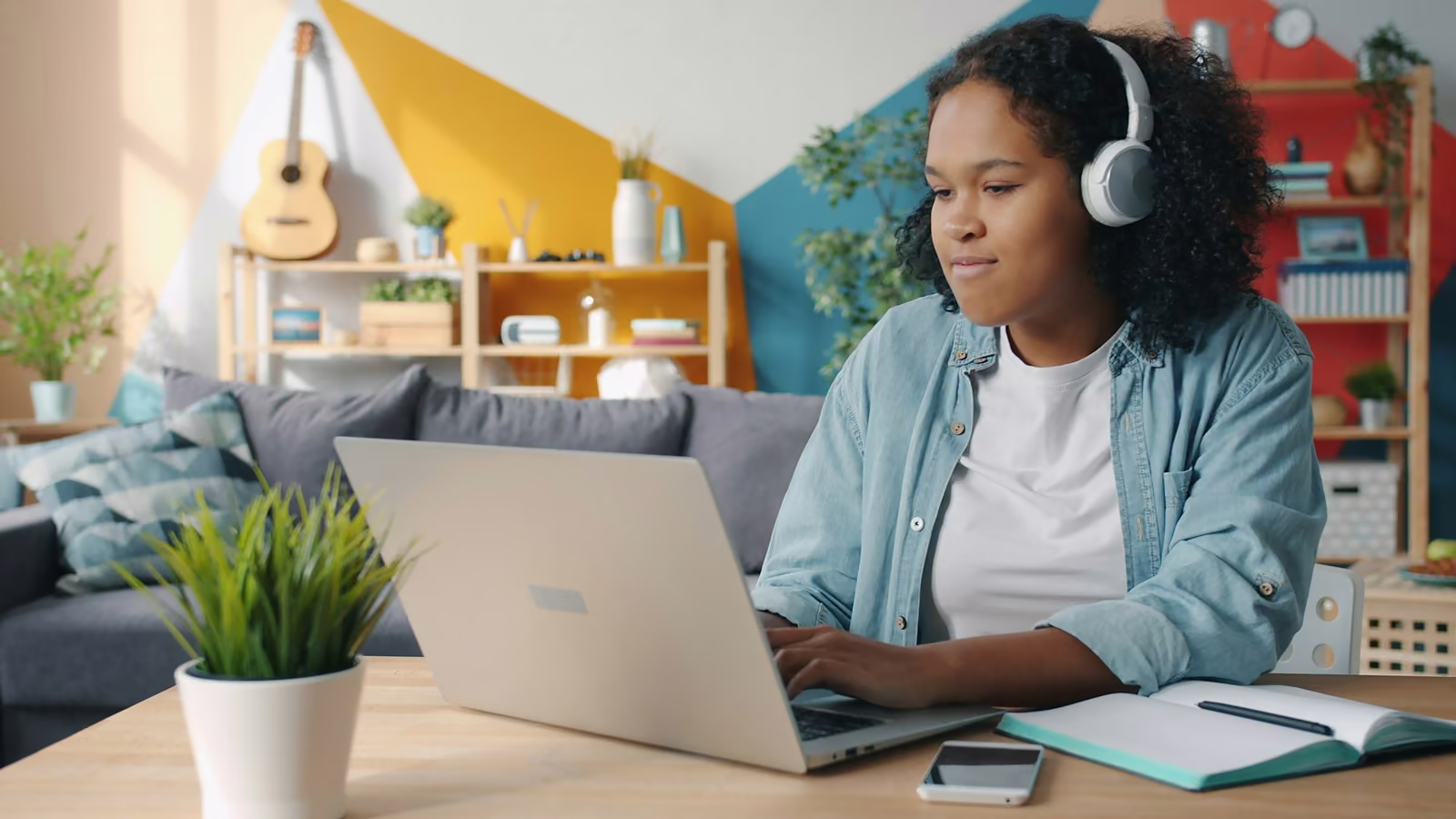 A student with headphones following a class on a laptop