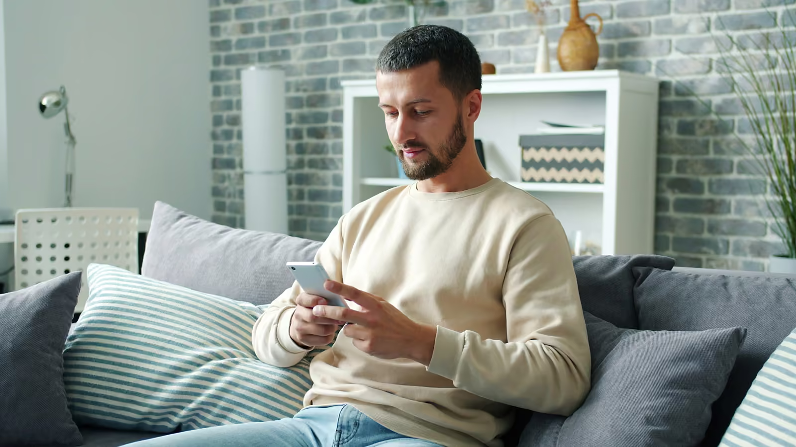 A father on the sofa at home, reading a message on his phone