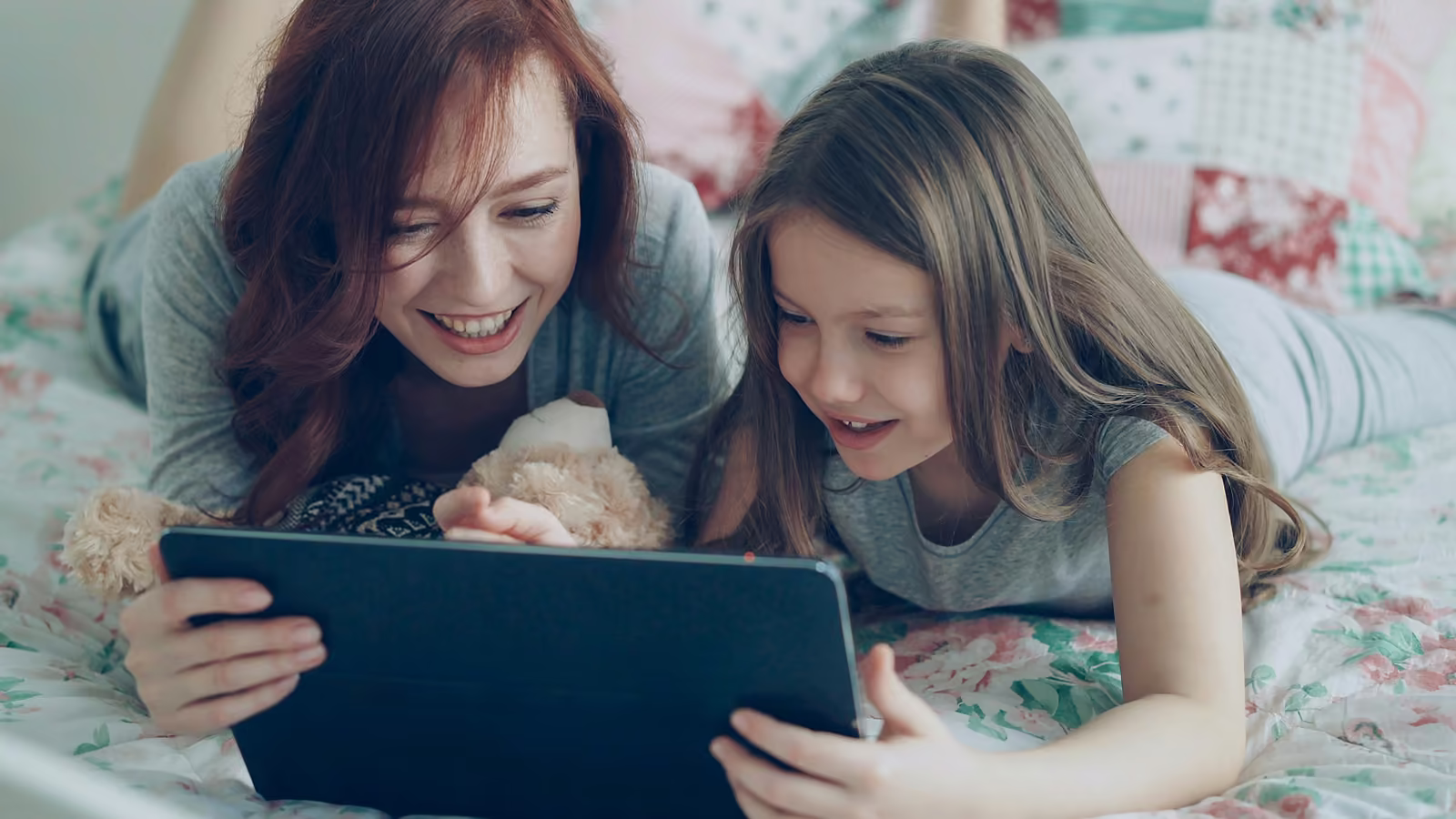 A mother and daughter looking at a tablet together, smiling