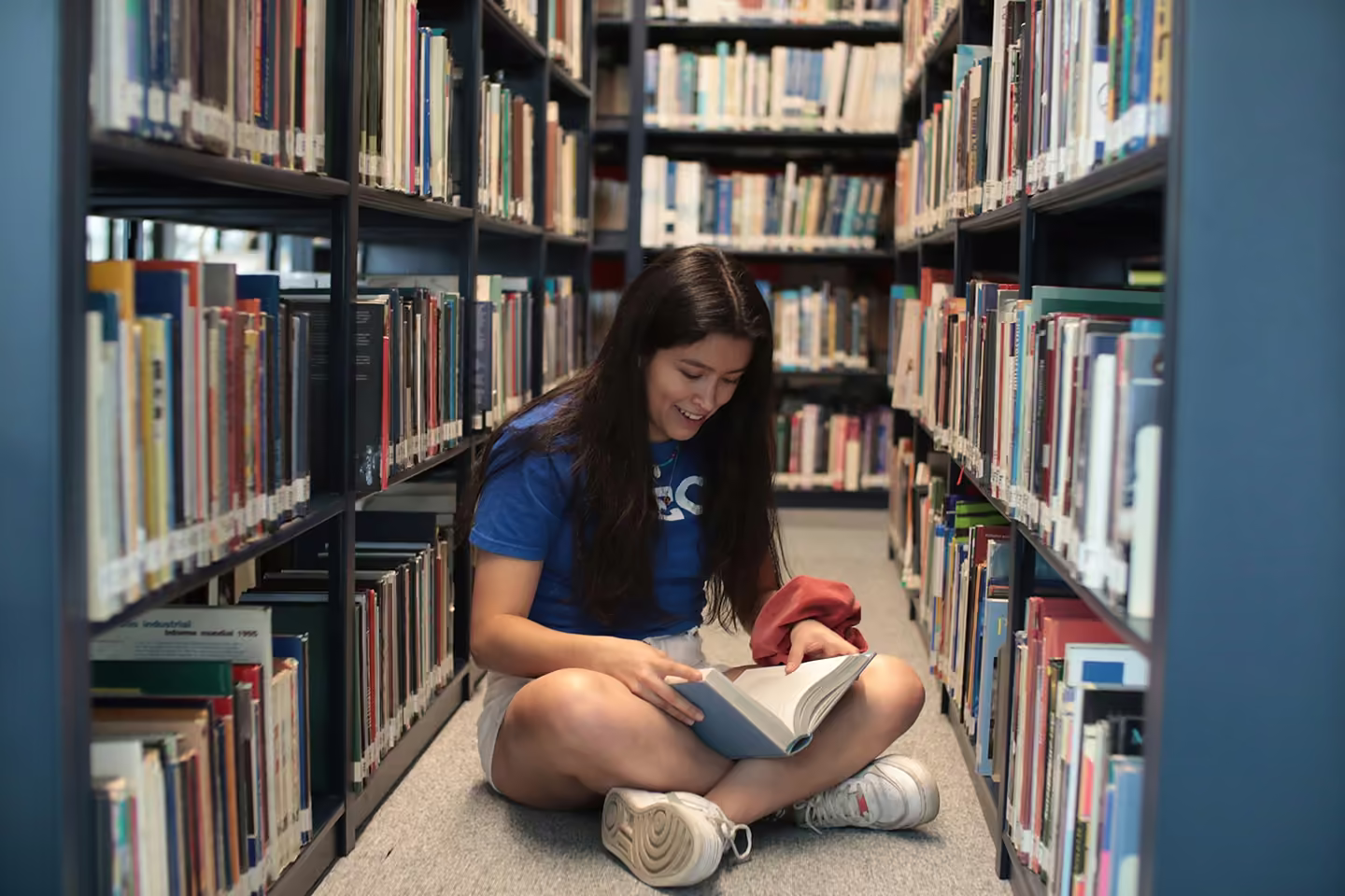A student sitting on the library floor, reading