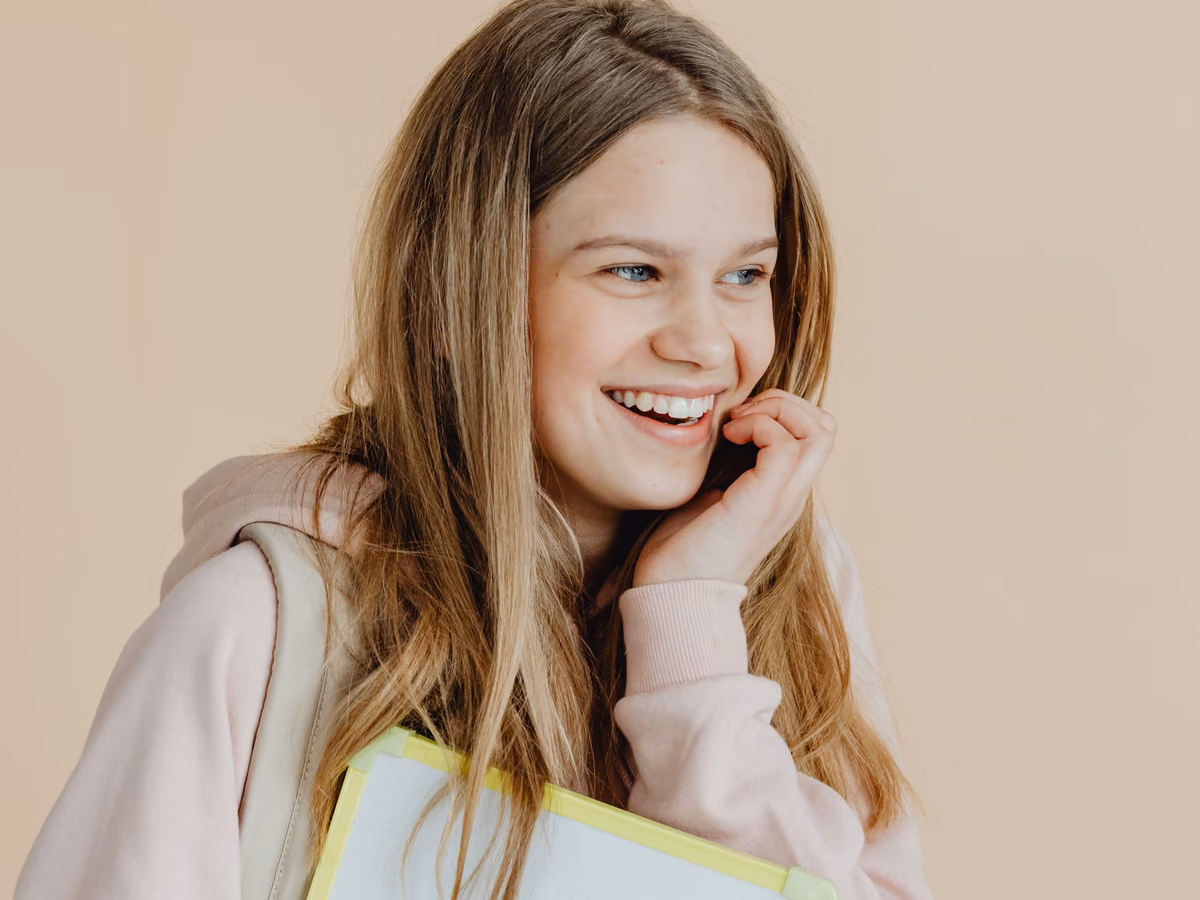 A happy student laughing as she holds her notebooks