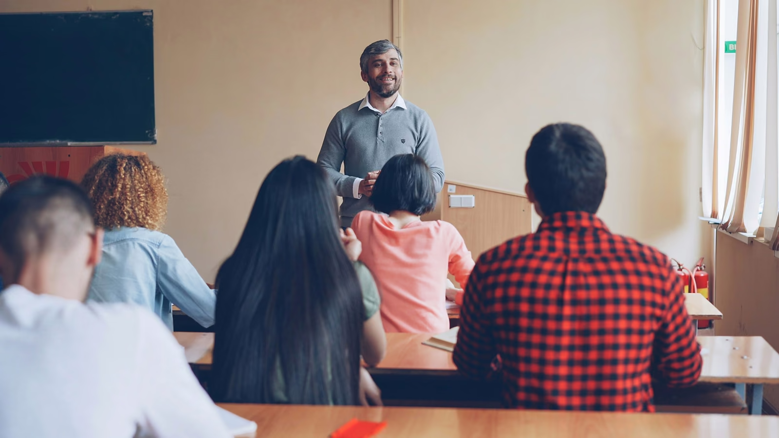 A teacher at the front of a lecture room, students listening